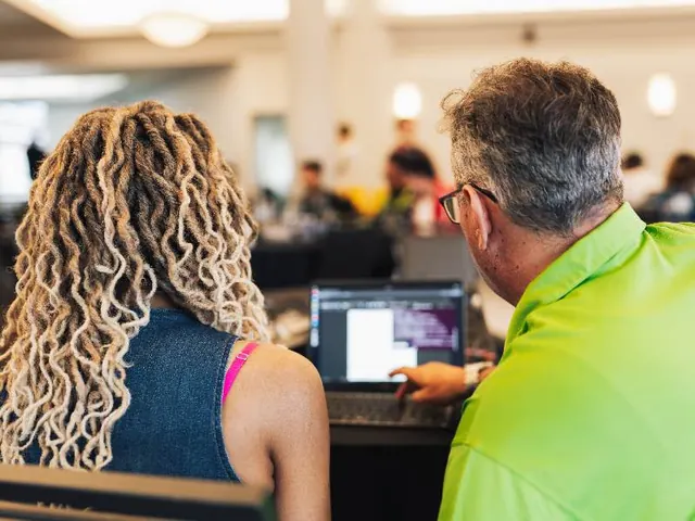 A mentor walking a participant through her project on a laptop